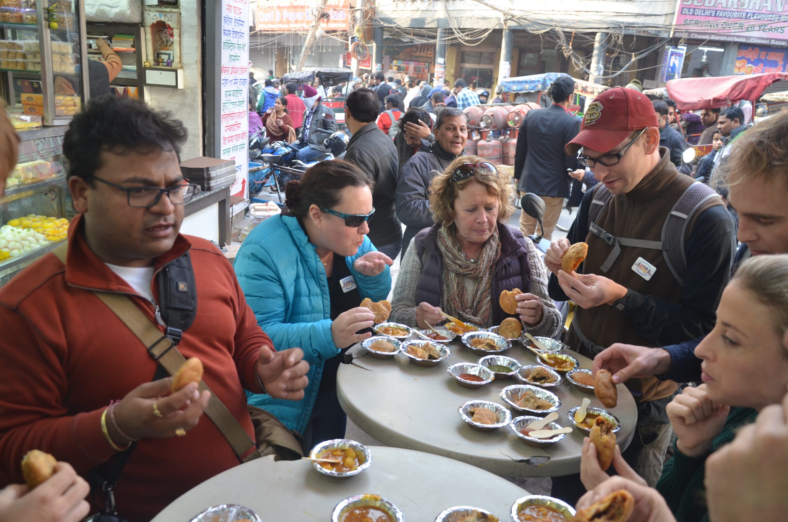 busy street food stall in Delhi with locals eating fresh samosa and chaat in crowded market